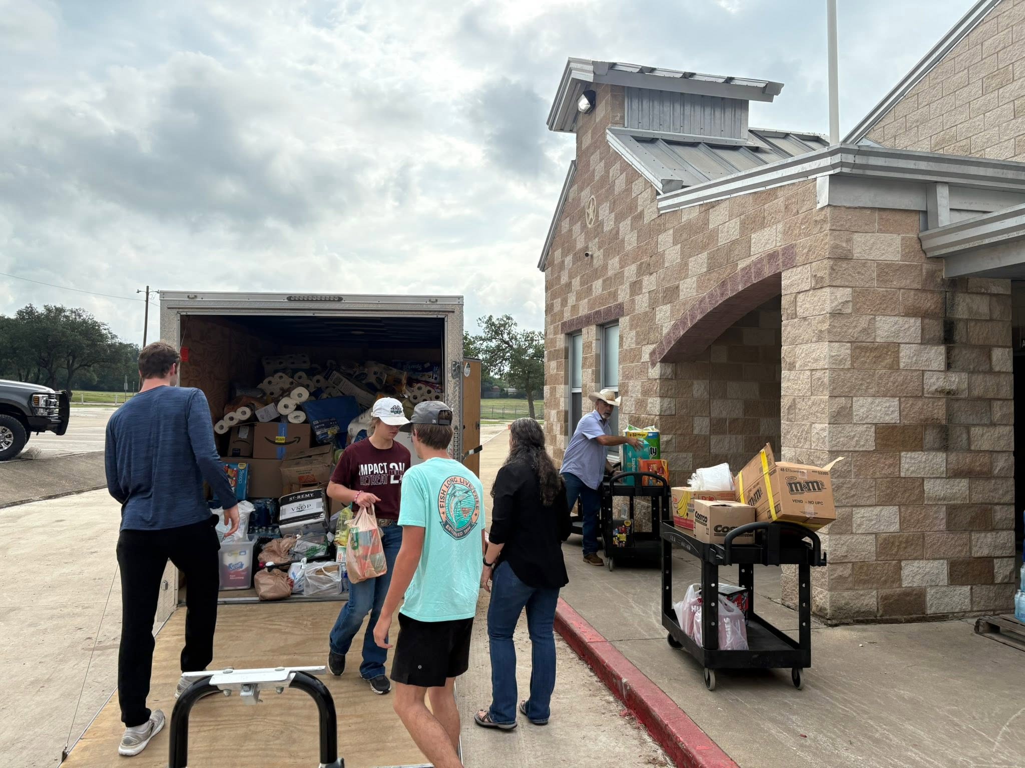 Community helpers unload the J-STAR trailer during the Kerrville flood-relief delivery.