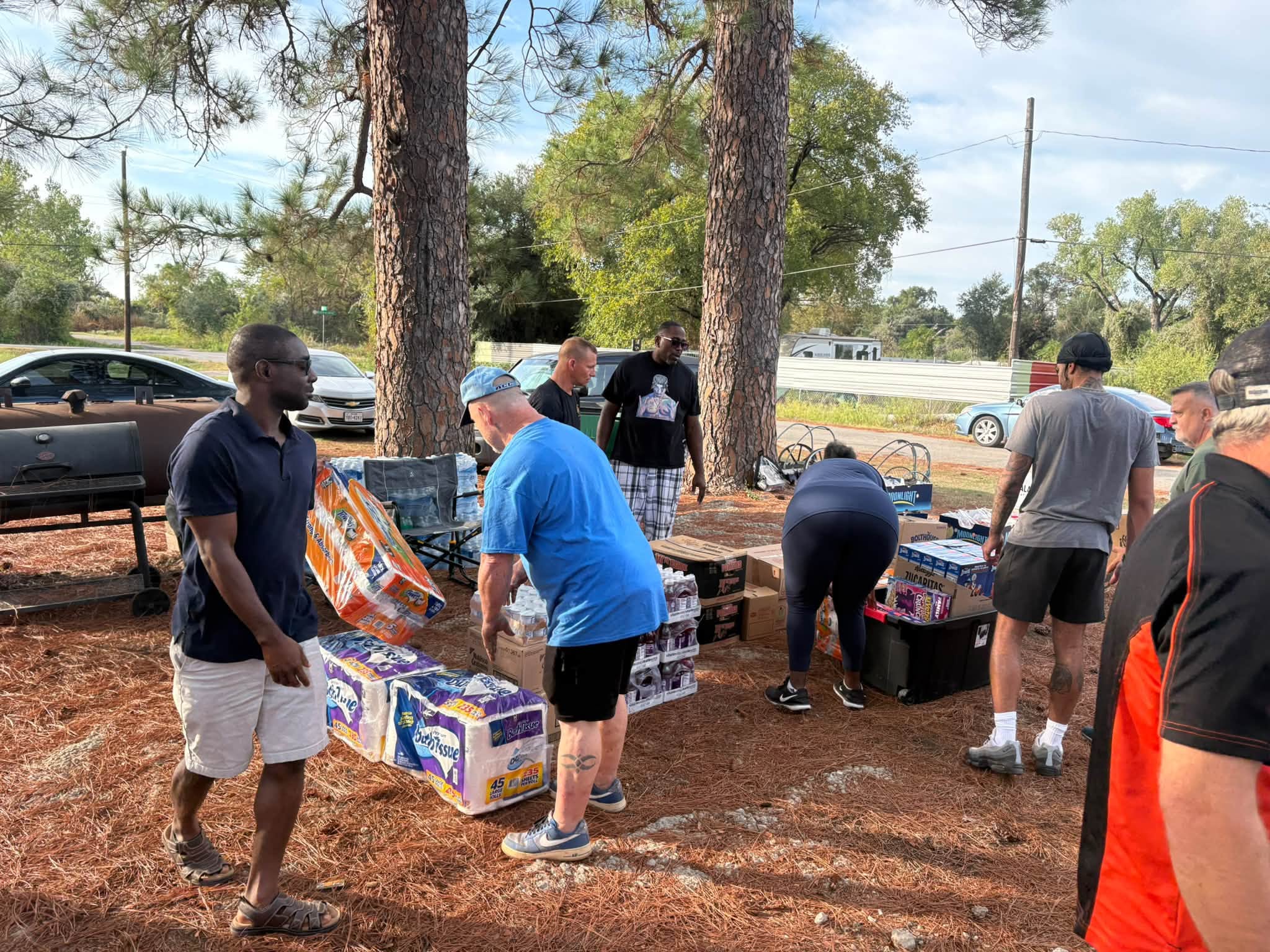 Volunteers arrange water and relief supplies under the trees in Sand Branch.